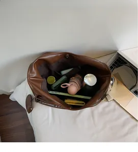 Vista dall'alto della grande borsa tote in ecopelle marrone con interno spazioso e oggetti