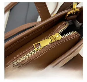 Detail shot of smooth golden metal zipper and dark brown textured leather handbag