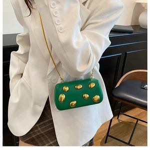 Dettaglio della pochette da sera rigida verde con decorazioni metalliche dorate