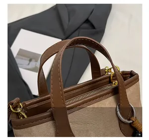 Detail of two-tone bucket bag featuring brown leather handles and khaki twill fabric