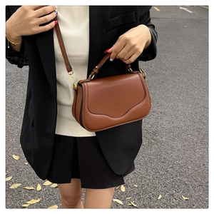 Gros plan d'un sac besace vintage en cuir marron avec des finitions métalliques dorées