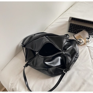 Detailed close-up of glossy black PU leather texture and silver zipper on tote bag