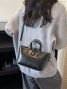 Classic black polished leather handbag with top handle and adjustable shoulder strap