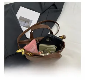 Detail showing internal capacity of the brown bucket bag with gold zipper and essentials