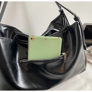 Detailed view of large black tote bag featuring a front zipper pocket for tablet storage