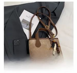 Detail of a mini two-tone crossbody bag with wooden bead charm and brown leather strap