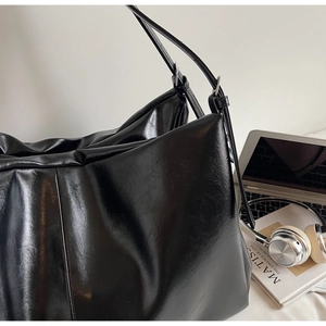 Macro shot of large black pleated tote bag with sleek PU leather finish and shoulder strap