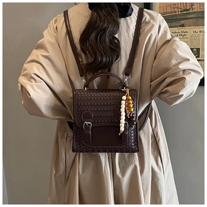 Dettaglio zaino in pelle intrecciata marrone scuro con fibbia e nappa di perline
