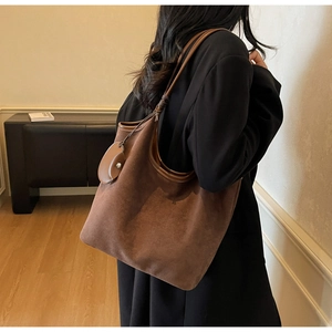 Dettaglio macro della borsa hobo in pelle scamosciata marrone con tracolla annodata