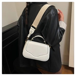 Détail du sac de selle en cuir PU blanc avec large bandoulière en textile crème doré
