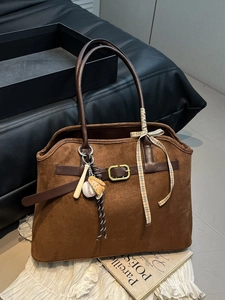 Sac fourre-tout en daim marron avec anses en cuir et breloques de sport sur fond vintage