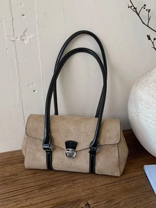 Retro khaki suede underarm bag with black leather straps and silver buckle on wood