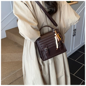 Dettaglio borsa intrecciata marrone con perline di legno e fibbie in stile vintage