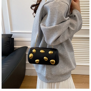 Dettagli della pochette nera con ornamenti metallici dorati irregolari surrealisti