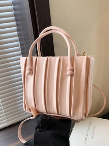 Sac seau plissé rose avec bandoulière sous une lumière naturelle de fenêtre