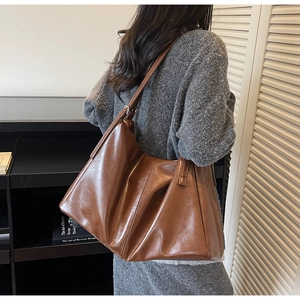 Brown soft leather large tote bag shown on shoulder in a retro minimalist lifestyle setting