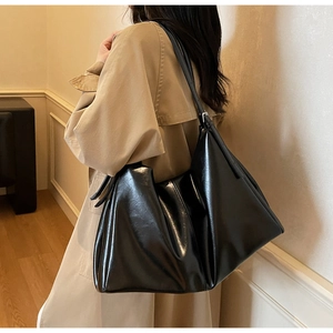 Detailed shot of large black glossy leather tote bag with adjustable shoulder strap