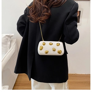 Modella con borsa a scatola bianca con pois metallici dorati e tracolla a catena