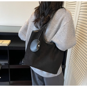 Dettaglio di una grande borsa tote in pelle scamosciata nera con borsellino tondo abbinato