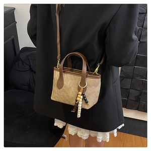 Detail of vintage crossbody bag with wooden bead charm and gold-tone metal hardware