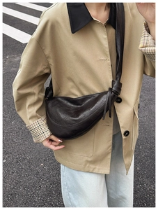 Detail of dark brown leather croissant bag with knotted shoulder strap on a model