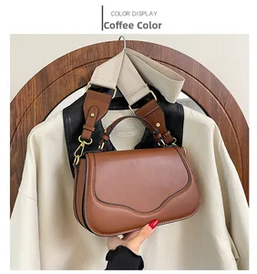 Détail du sac selle marron café avec large bandoulière crème et finitions dorées