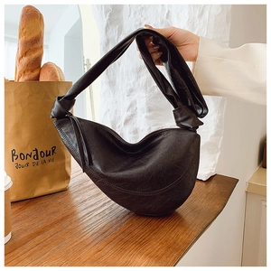 Detailed view of the knotted leather handle and soft pleated texture of a black hobo bag