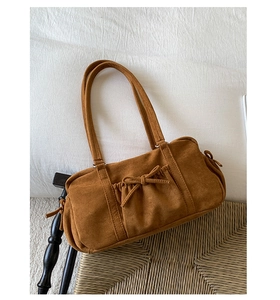 Détail d'un sac hobo en daim marron vintage avec nœud décoratif et texture à cordon