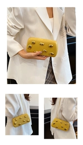 Vista a tre angoli di una pochette gialla con accenti decorativi in metallo dorato a forma di sassi