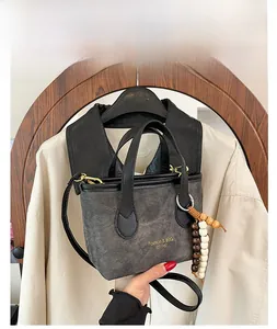 Detail of dark gray bucket bag with wooden bead charm and vintage yellow branding logo