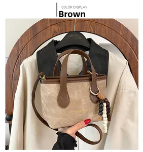 Detail of a brown canvas mini tote bag featuring leather trim and decorative beads