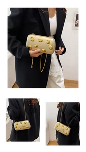 Dettaglio pochette rigida dorata con sfere metalliche artistiche e tracolla a catena