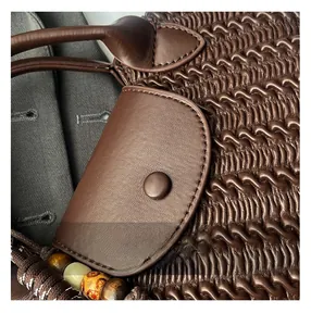 Detail der dunkelbraunen Ledertasche mit Wellensteppung und Perlen-Webverzierung