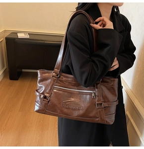 Detail showing the embossed Noronoro logo and smooth leather texture of a brown tote bag