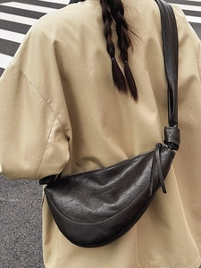 Classic leather dumpling crossbody bag with knotted strap shown on model in urban setting