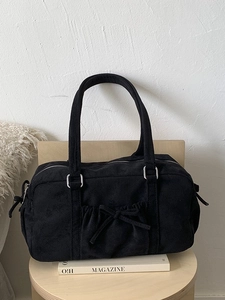 Sac bowling vintage en suédine noire avec détails de cordon sur un tabouret minimal