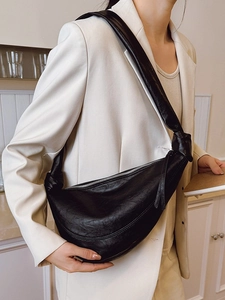 Modern black leather crescent bag with stylish knotted shoulder strap and silver zipper