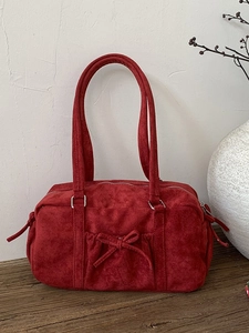 Sac bowling en daim rouge avec nœud sur une table en bois, sac à main vintage