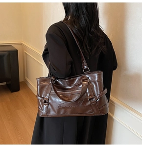 Detail of deep brown tote bag with embossed logo on glossy textured leather surface