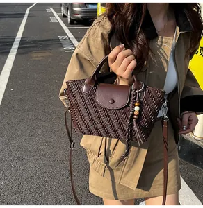 Detail of dark brown woven texture handbag with wooden bead charm and crossbody strap