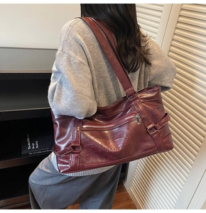 Side view of a vintage burgundy tote bag with embossed logo and metal zipper pocket