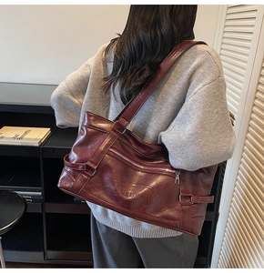 Deep burgundy leather tote bag with embossed logo shown on shoulder in stylish interior
