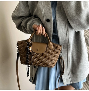 Detail of woven texture handbag with leather flap and decorative beaded strap