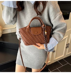Detail of brown woven texture handbag featuring beaded tassel and circular handle