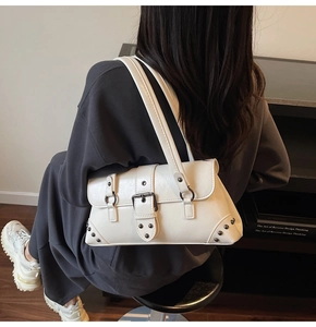 Détail d'un sac sous les bras en cuir blanc avec rivets et boucle sur un modèle