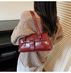 Détail du sac à bandoulière rétro bordeaux avec boucle en cuir et rivets en métal