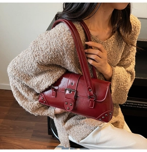 Détail du sac à bandoulière bordeaux en similicuir avec boucle vintage et rivets