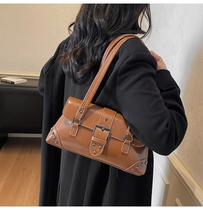 Détail du sac baguette marron vintage avec clous argentés et boucle sur cuir poli