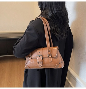Détail du sac de moto vintage marron avec boucles argentées et rivets métalliques sur modèle