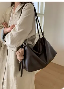Detail of large brown vintage tote bag with plush dog charm and smooth zipper closure